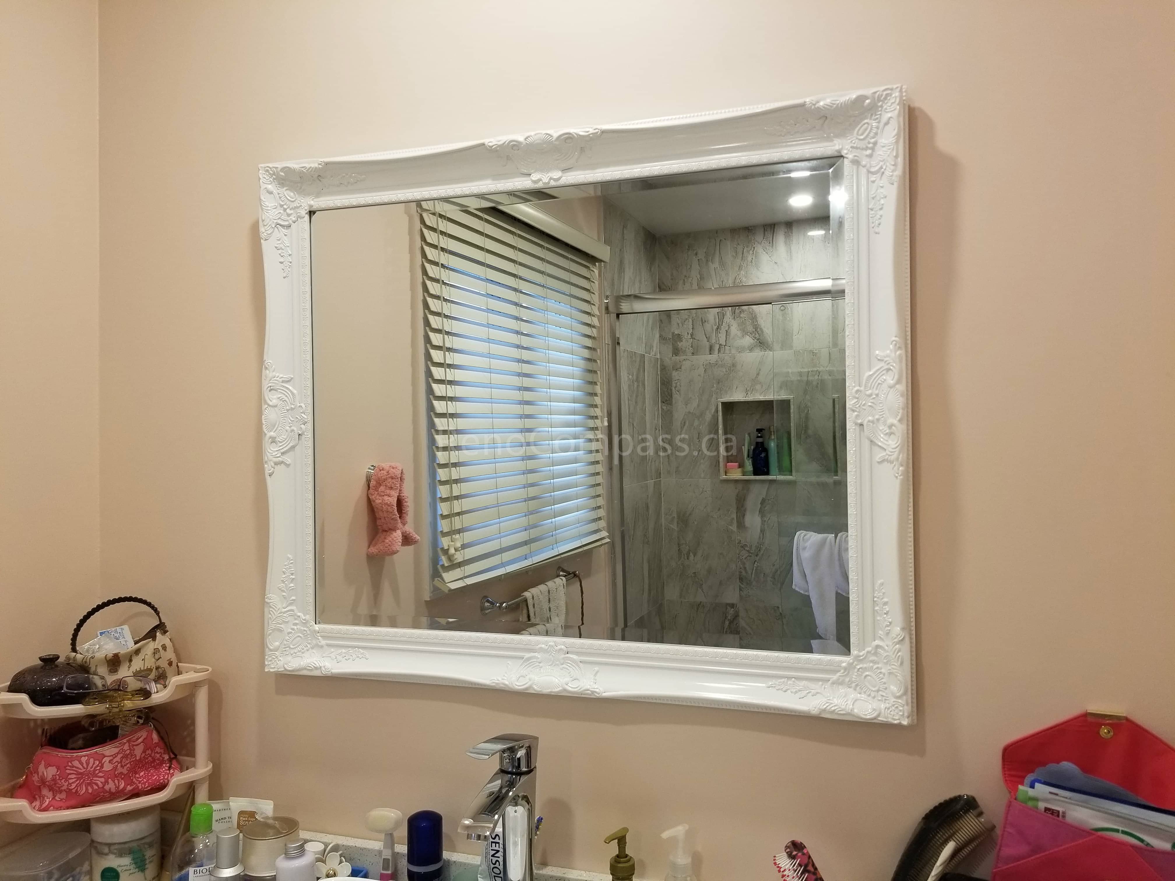 This Markham bathroom renovation showcases a newly updated vanity area paired with a decorative framed mirror that enhances the brightness and visual space of the bathroom. The mirror reflects the upgraded shower with new wall tiles and built-in niche, highlighting the cohesive design of this full bathroom remodel. The renovation delivers improved functionality, elegant finishes, and a refreshed modern look for everyday comfort.