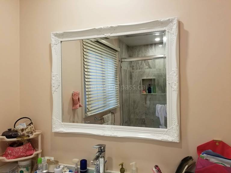 This Markham bathroom renovation showcases a newly updated vanity area paired with a decorative framed mirror that enhances the brightness and visual space of the bathroom. The mirror reflects the upgraded shower with new wall tiles and built-in niche, highlighting the cohesive design of this full bathroom remodel. The renovation delivers improved functionality, elegant finishes, and a refreshed modern look for everyday comfort.