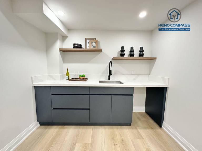 This Richmond Hill interior renovation features a custom basement wet bar with modern flat-panel cabinetry, quartz countertops, open wood shelving, and integrated sink fixtures. The clean lines and neutral finishes create a functional and stylish entertainment area. Designed and built by a Toronto renovation company, the space enhances both usability and home value.