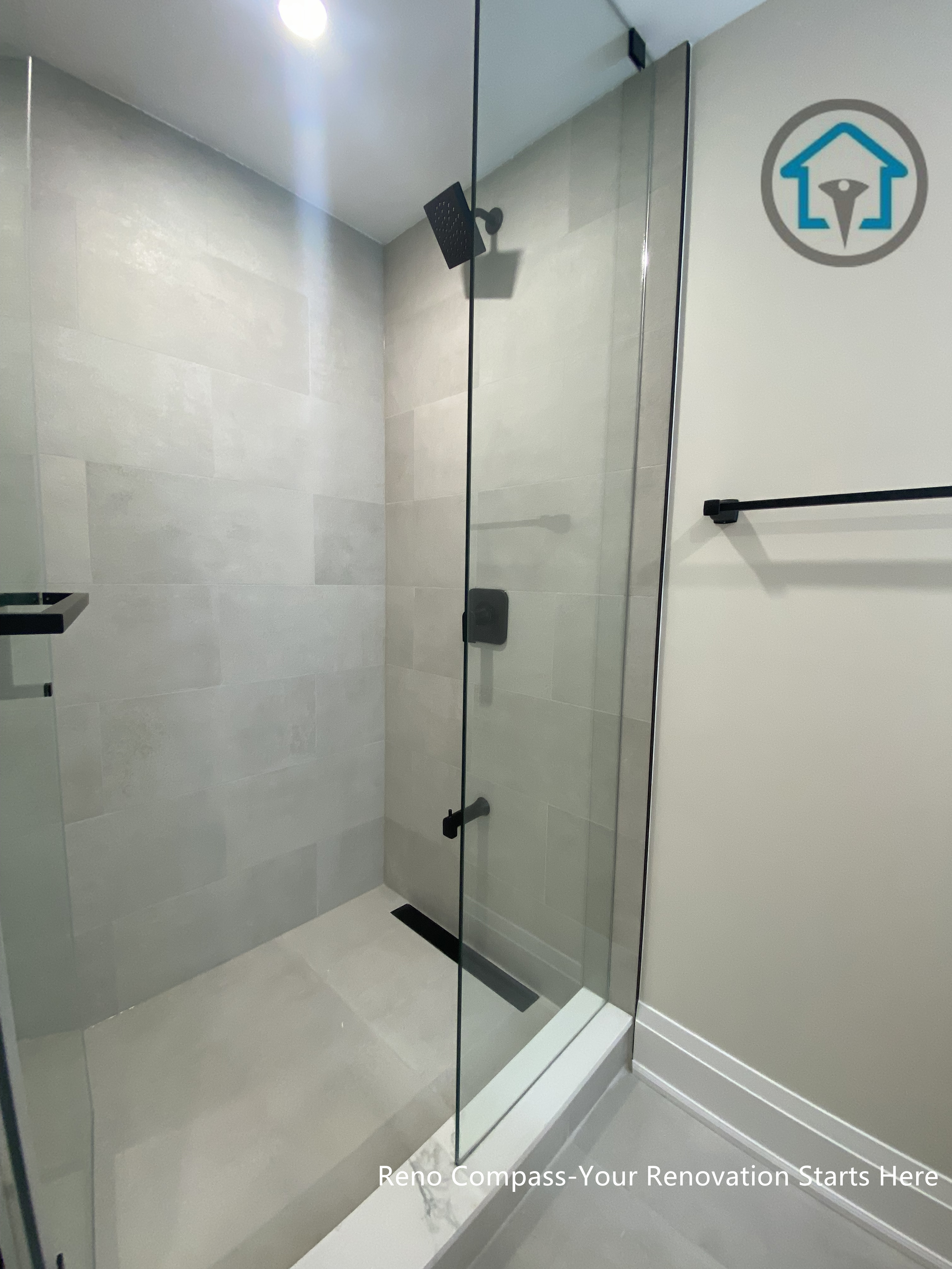 This image highlights a modern bathroom renovation in Richmond Hill, featuring a frameless glass shower with clean tile finishes and matte black fixtures. The minimal detailing, neutral tones, and precise glass installation create a bright, functional, and timeless shower space. Designed and completed by Reno Compass, this bathroom renovation reflects a practical yet refined approach to everyday comfort and durability in Richmond Hill homes.