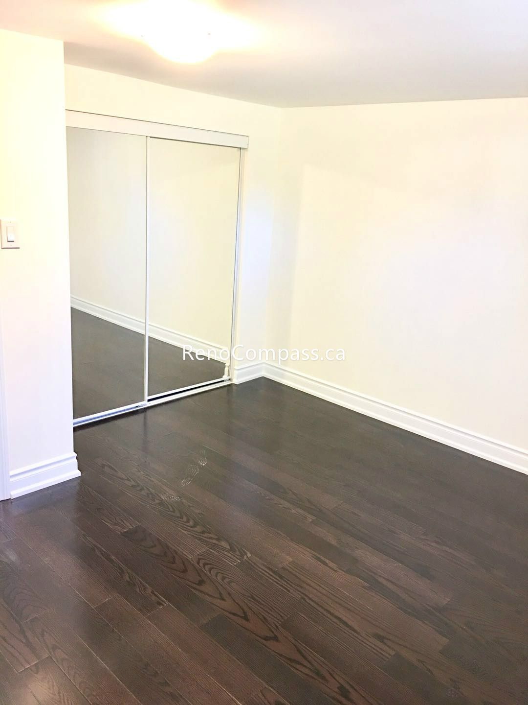 This Toronto basement renovation features a newly finished bedroom with rich hardwood flooring, fresh neutral walls, and a built-in closet with sliding doors. The clean layout and warm lighting create a comfortable and functional living space ideal for rental or family use. Completed by a professional Toronto renovation company, this basement bedroom upgrade enhances both property value and everyday living comfort.