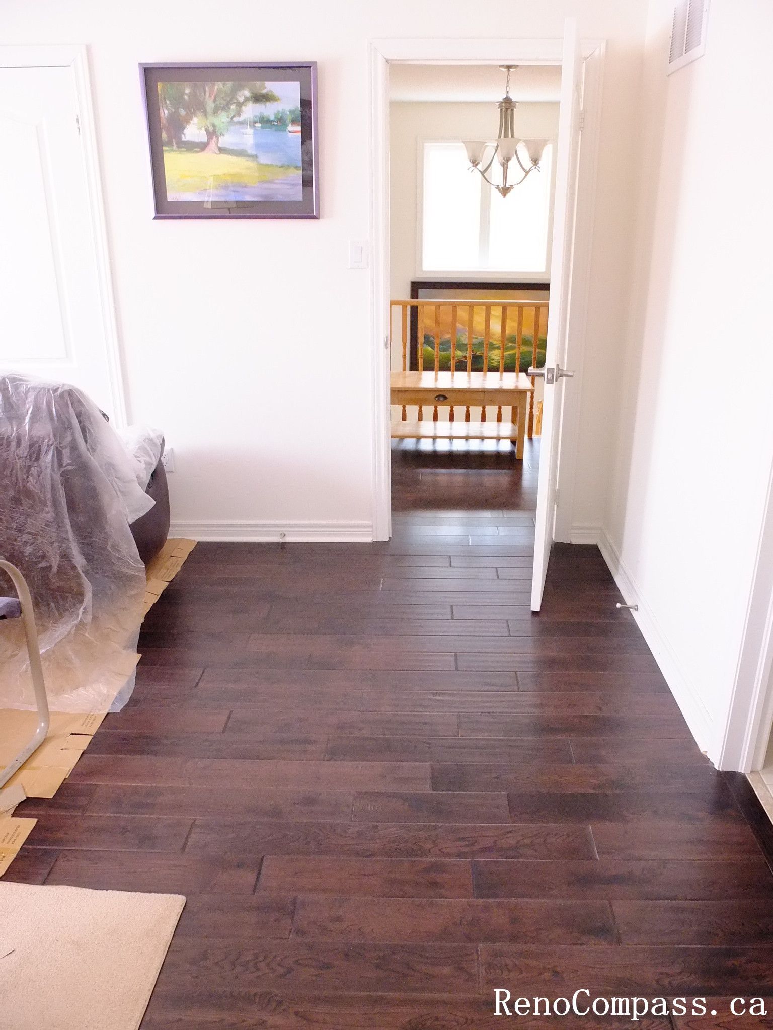 Toronto home hardwood flooring installation featuring deep-toned wood floors throughout the hallway and upper level. This professional flooring renovation enhances brightness, durability, and visual continuity, completed by Reno Compass for a clean and modern interior upgrade.