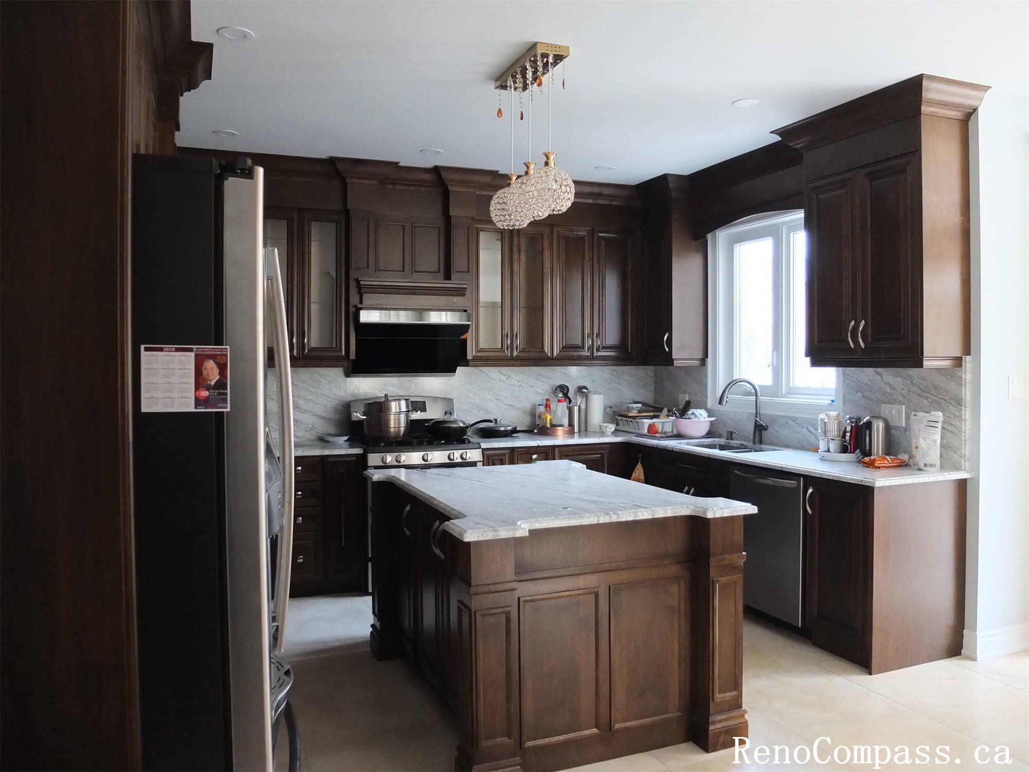 This Richmond Hill kitchen renovation showcases elegant dark wood cabinetry, a marble countertop island, and modern stainless steel appliances. The upgraded layout improves functionality and storage while creating a warm and sophisticated kitchen space for everyday family cooking and gatherings.