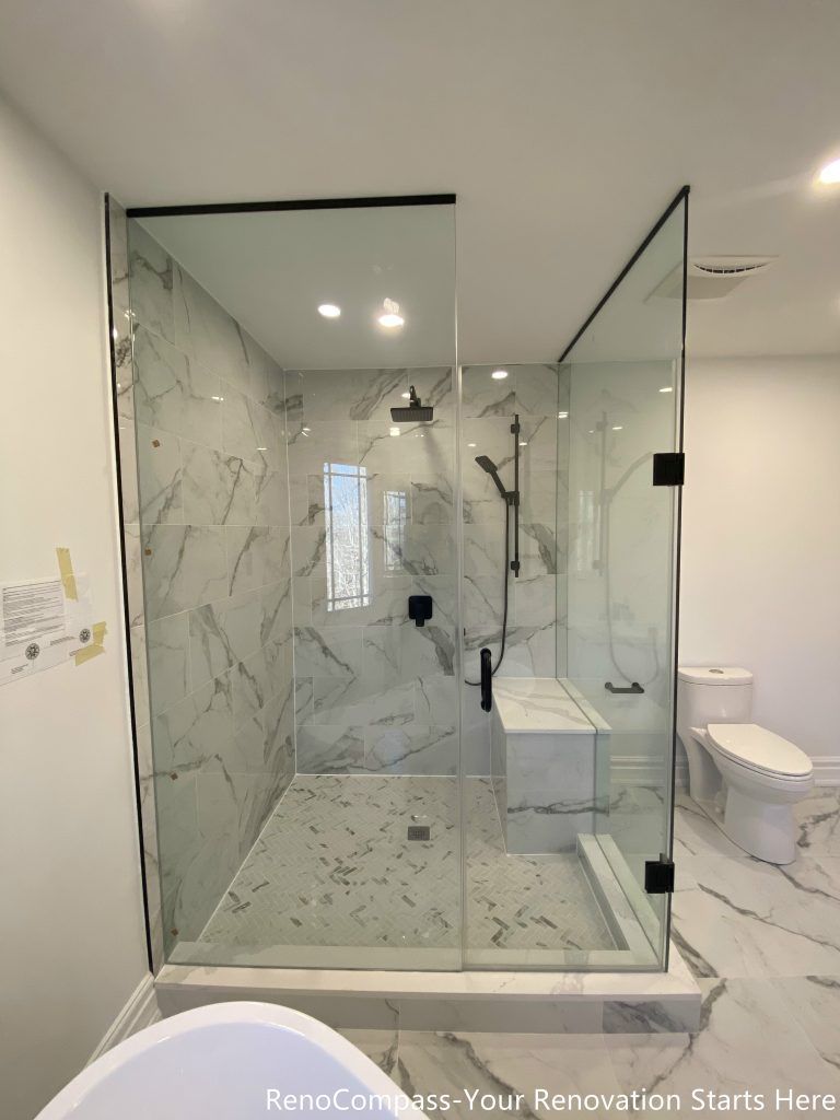 This Thornhill bathroom renovation showcases a detailed walk-in shower interior finished with marble-look porcelain wall tiles and a textured shower base. Matte black rain shower and handheld fixtures create a bold contrast against the light stone surfaces, adding a modern and refined aesthetic. The frameless glass enclosure enhances brightness and visual openness, while the carefully selected materials ensure durability, easy maintenance, and long-term daily comfort.