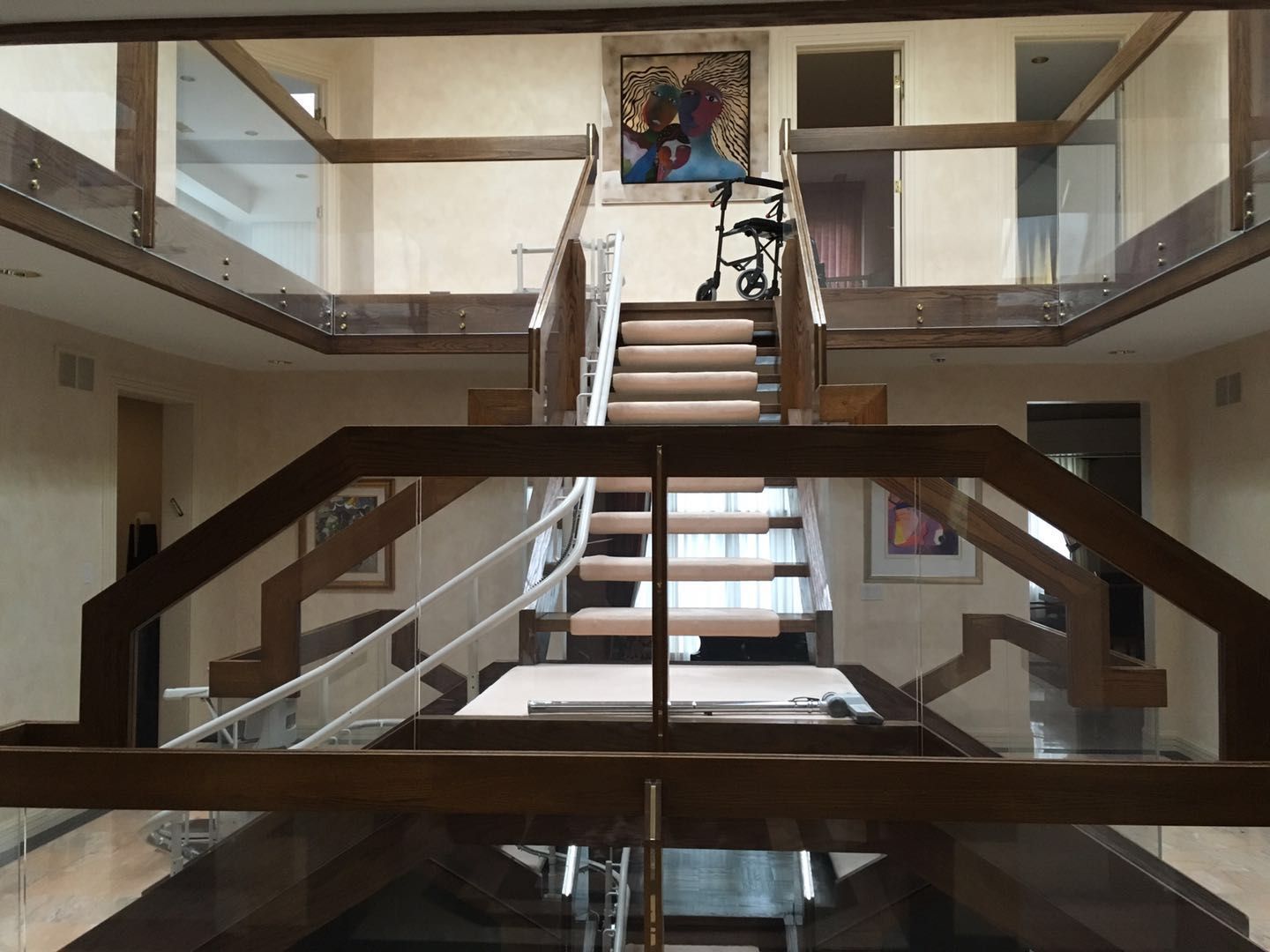 This Toronto interior renovation showcases a stunning custom staircase design with wood and glass railings, creating a striking architectural focal point within the home. The open-concept layout features clean lines, modern finishes, and elegant lighting that enhances the sense of space and sophistication. Glass guardrails on the upper level allow natural light to flow freely, adding brightness and visual continuity throughout the interior. Completed by a professional Toronto renovation company, this project highlights refined craftsmanship, structural upgrades, and luxury residential design.