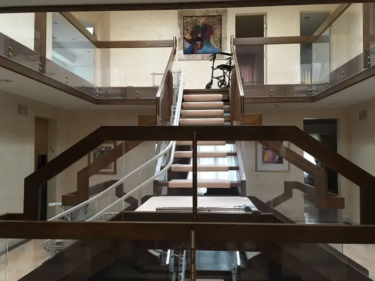 This Toronto interior renovation showcases a stunning custom staircase design with wood and glass railings, creating a striking architectural focal point within the home. The open-concept layout features clean lines, modern finishes, and elegant lighting that enhances the sense of space and sophistication. Glass guardrails on the upper level allow natural light to flow freely, adding brightness and visual continuity throughout the interior. Completed by a professional Toronto renovation company, this project highlights refined craftsmanship, structural upgrades, and luxury residential design.