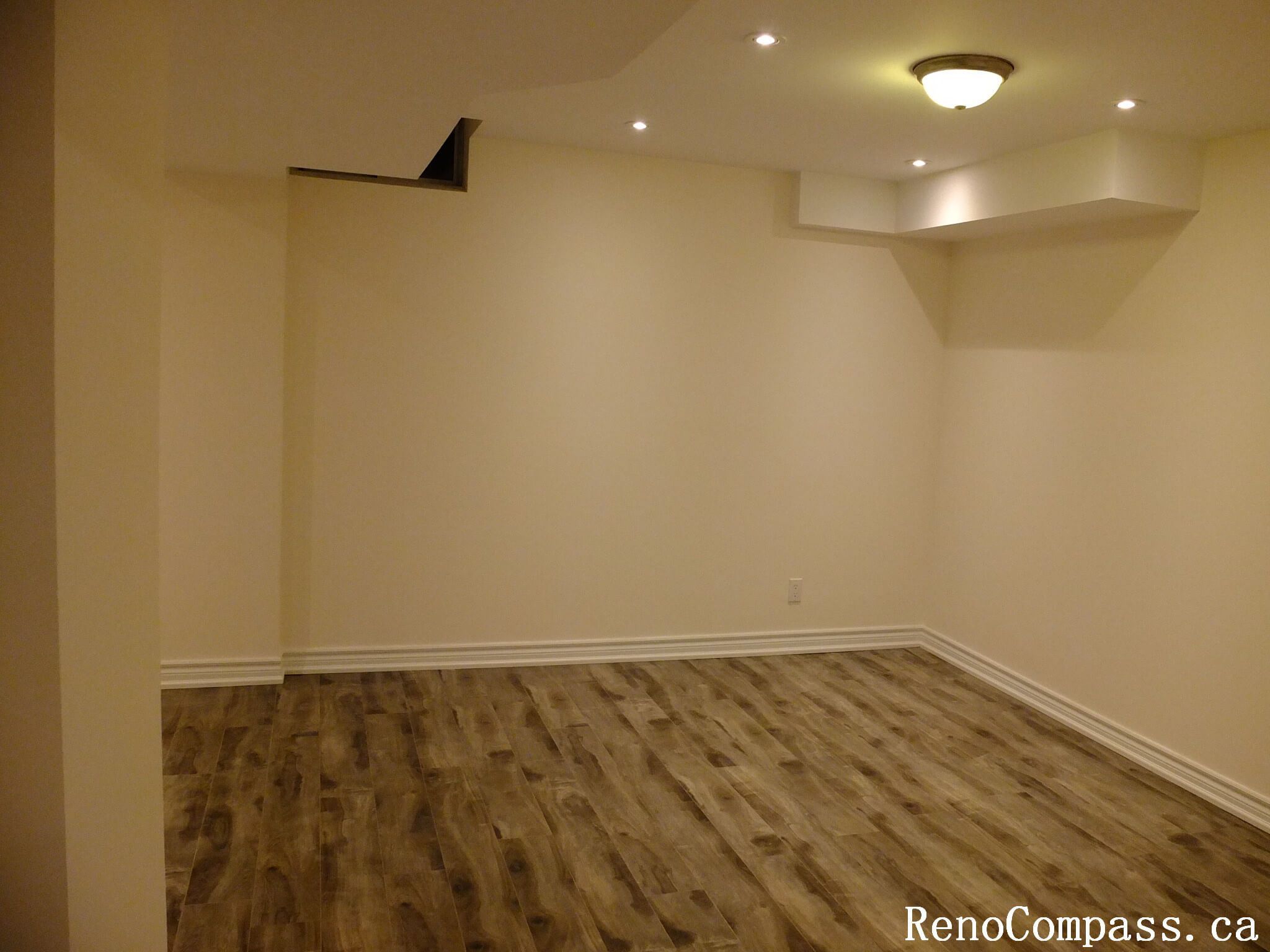 This Markham basement renovation highlights a spacious finished basement living area featuring recessed pot lights, durable wood-look vinyl flooring, and a clean neutral color palette. The open layout maximizes functionality and comfort, creating a versatile space ideal for a family room, home office, or recreational area in Markham.