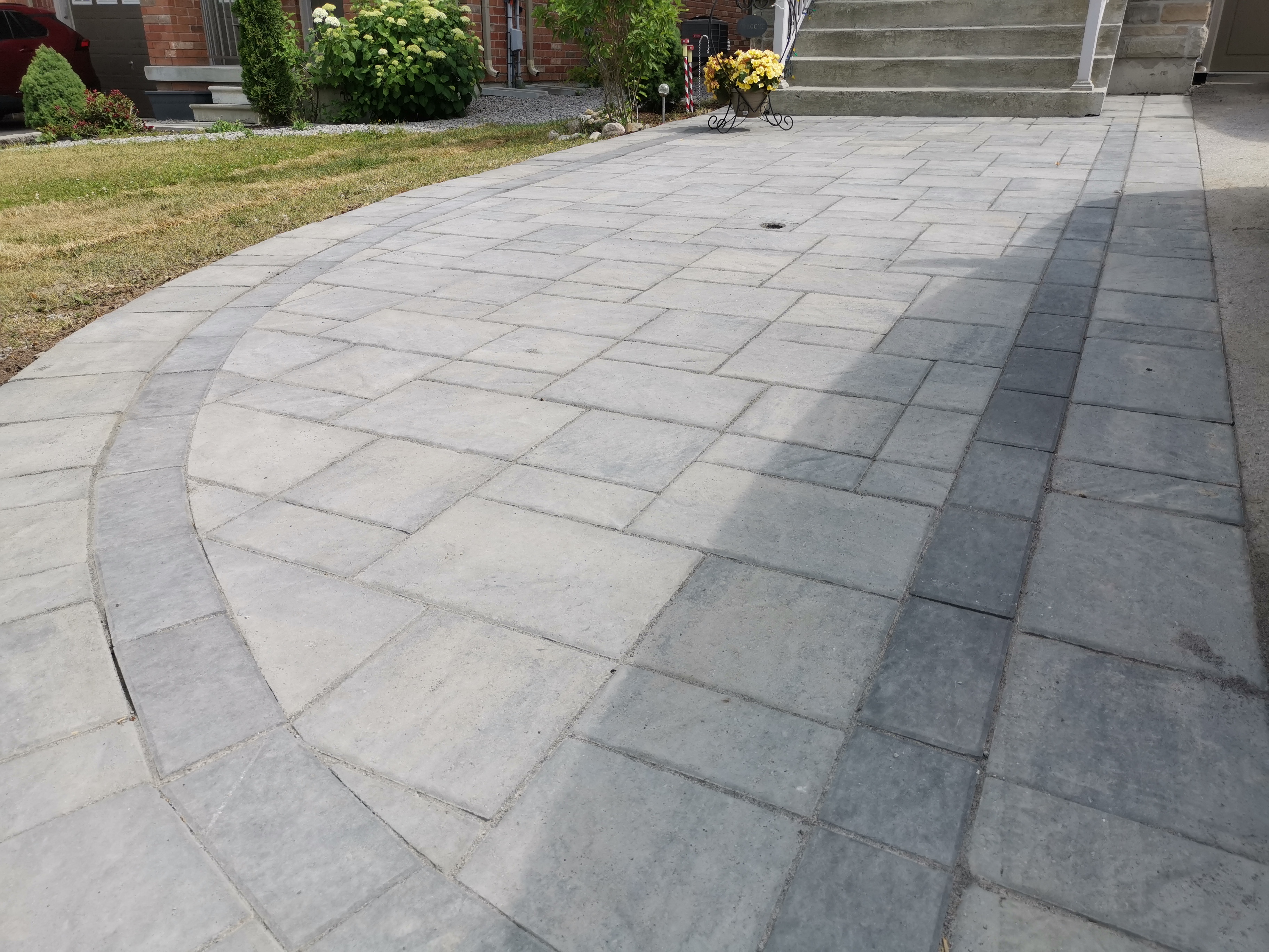 This Aurora interlocking driveway features a curved border detail that adds visual flow and refined craftsmanship to the overall layout. Large-format concrete pavers are precisely installed to create a smooth, durable surface while the contrasting curved inlay defines the driveway edge and enhances architectural balance. The clean alignment supports proper drainage, long-term stability, and low maintenance. This professionally completed interlocking driveway detail improves curb appeal and functionality for residential properties in Aurora.