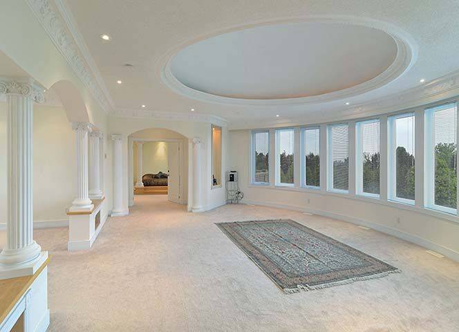 Spacious upper family room from a luxury Toronto home renovation featuring elegant architectural columns, large panoramic windows, and a distinctive circular ceiling design. The open layout creates a bright and comfortable gathering space for family relaxation and entertainment. This custom interior renovation was completed by Reno Compass, a trusted Toronto Renovation Company specializing in luxury home rebuilds and interior renovations across the Greater Toronto Area.