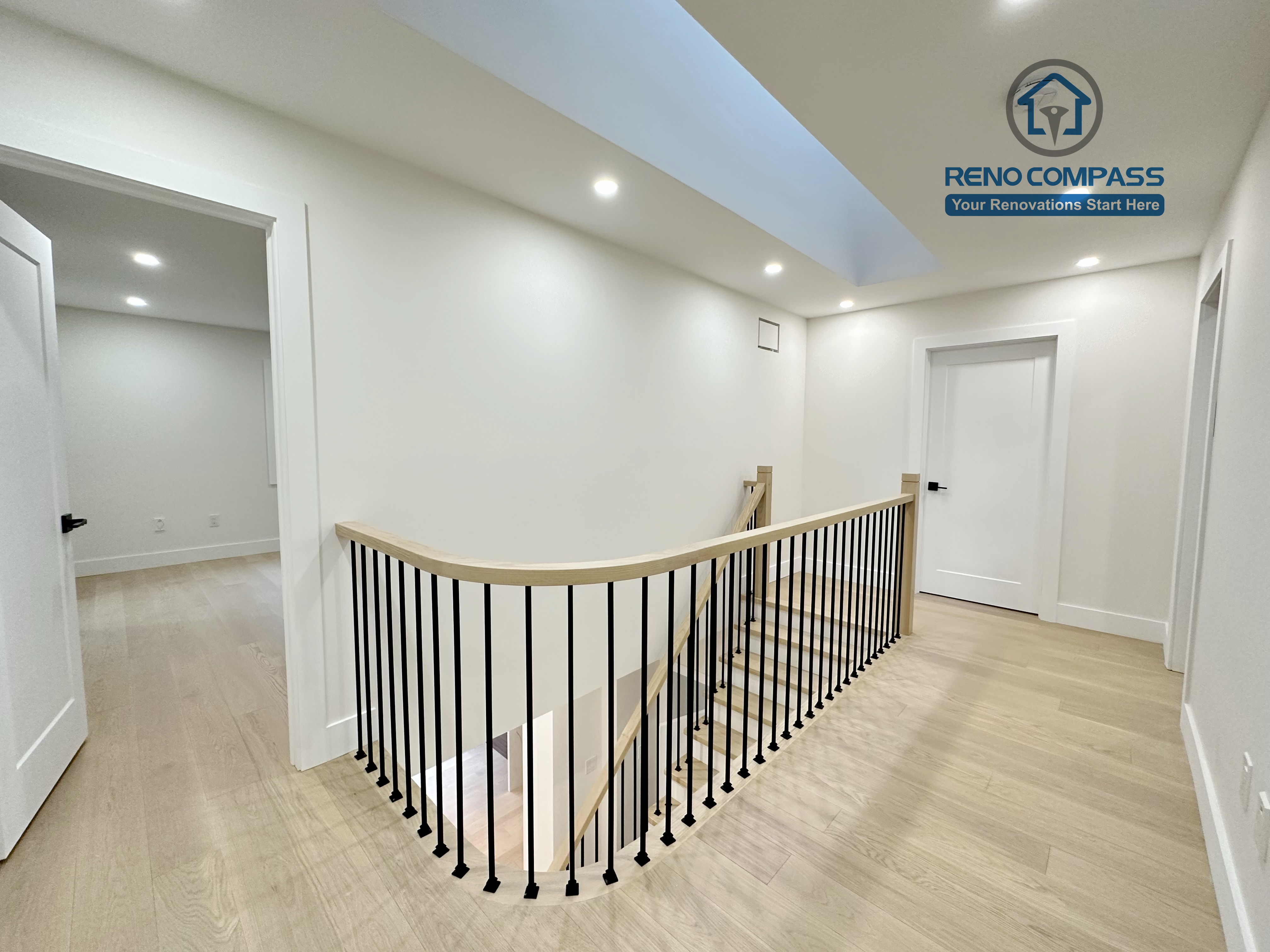 Upper-level hallway in a Richmond Hill home featuring light-tone hardwood flooring, modern stair railings with black balusters, recessed ceiling lights, and skylight-style ceiling detail for a bright, open feel.