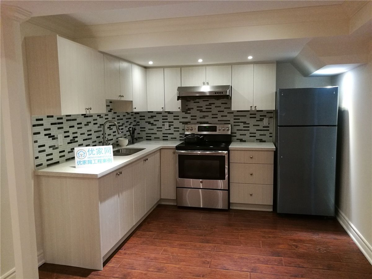 Modern kitchen renovation completed as part of a Toronto interior renovation project. Features include custom white cabinetry, mosaic tile backsplash, stainless steel appliances, recessed pot lights, and warm-toned flooring, creating a clean, functional, and contemporary kitchen layout.