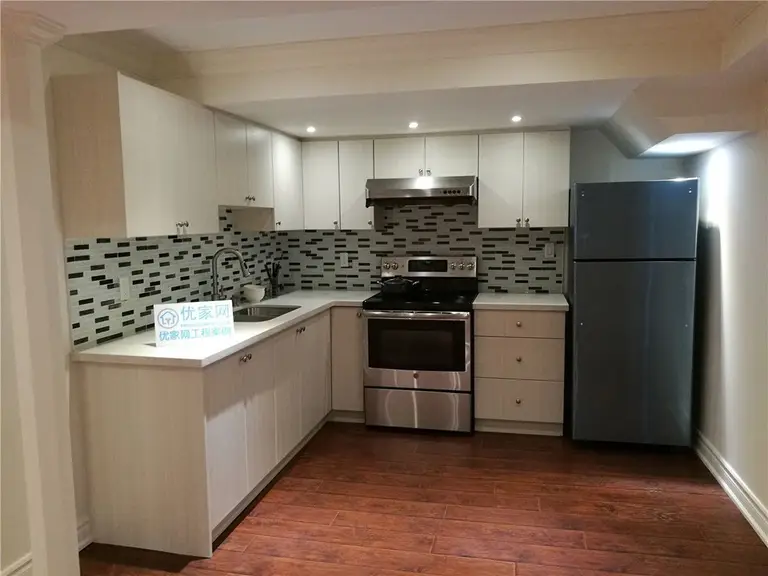 Modern kitchen renovation completed as part of a Toronto interior renovation project. Features include custom white cabinetry, mosaic tile backsplash, stainless steel appliances, recessed pot lights, and warm-toned flooring, creating a clean, functional, and contemporary kitchen layout.