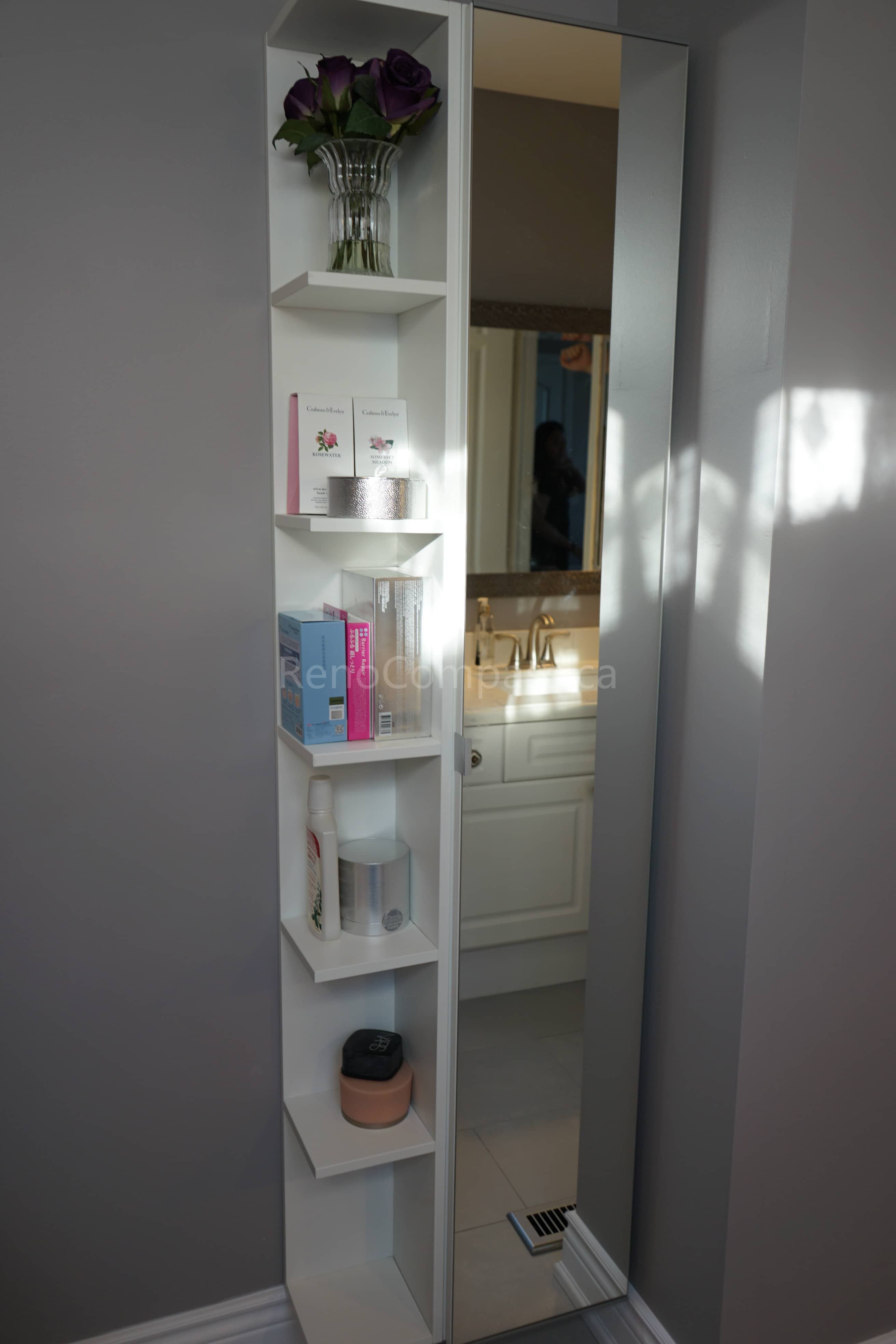 This bathroom renovation features a custom built-in vertical storage shelf designed to maximize space and organization. The sleek white shelving unit provides functional storage for toiletries and décor while maintaining a clean, modern aesthetic. Paired with a stylish vanity and soft lighting, this renovation enhances both practicality and elegance in the bathroom space.