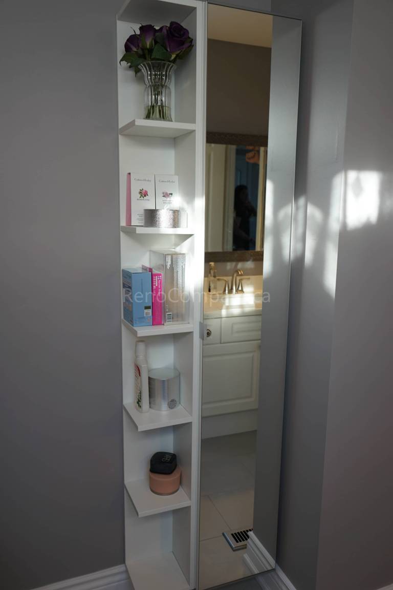This bathroom renovation features a custom built-in vertical storage shelf designed to maximize space and organization. The sleek white shelving unit provides functional storage for toiletries and décor while maintaining a clean, modern aesthetic. Paired with a stylish vanity and soft lighting, this renovation enhances both practicality and elegance in the bathroom space.