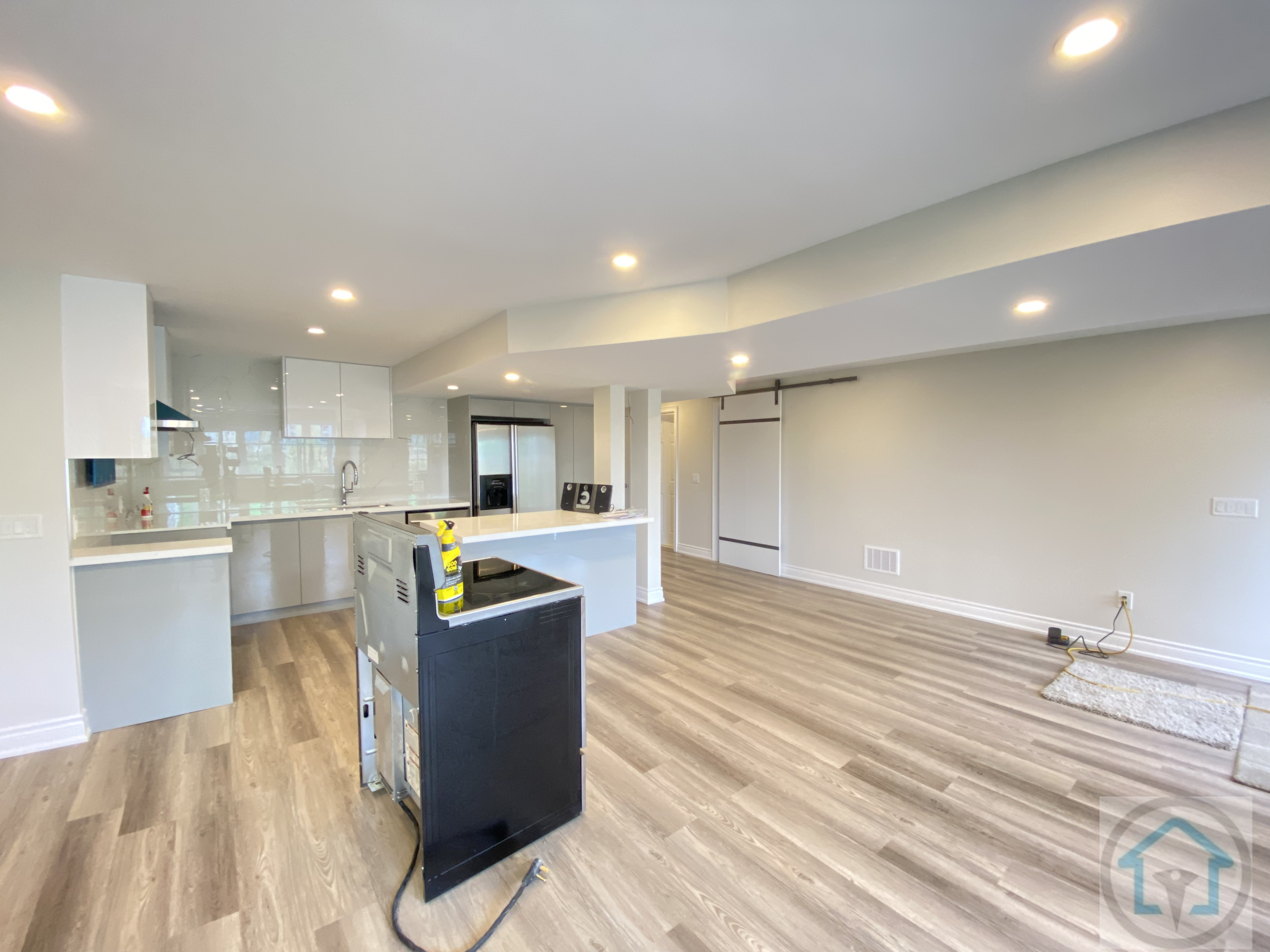 This Newmarket basement renovation showcases a spacious open-concept layout connecting the living area and kitchen. Continuous flooring, recessed ceiling lights, and clean structural lines create a bright, cohesive lower-level space designed for everyday living, entertaining, and flexible use.
