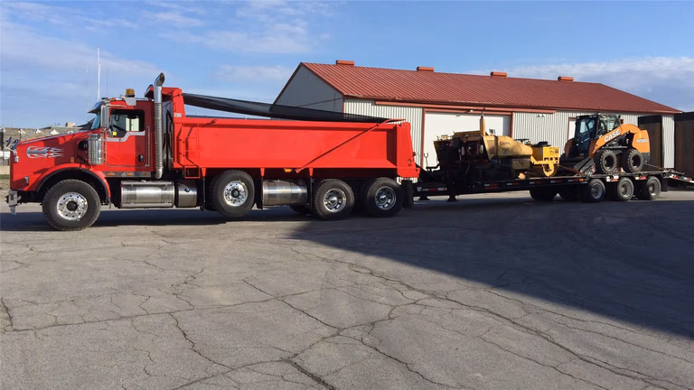 Heavy-duty construction truck transporting landscaping equipment and materials for a Toronto exterior renovation project. Professional logistics and machinery ensure efficient site preparation and smooth progress for large landscaping and driveway installations.